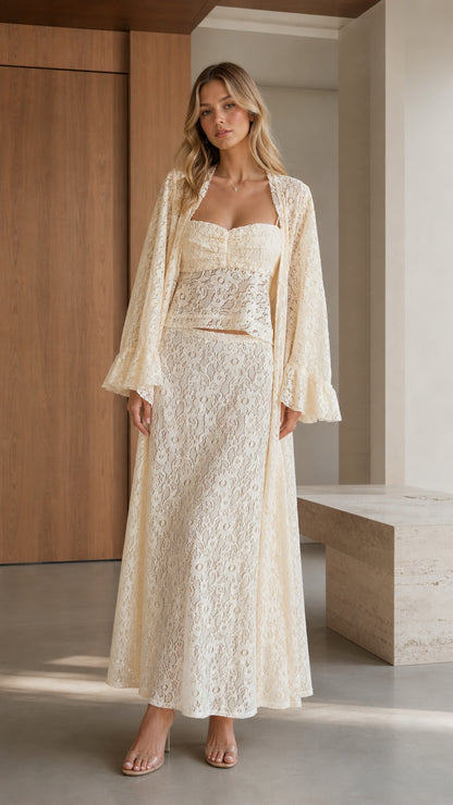 Front view of woman wearing cream three-piece lace crop top, maxi skirt, and robe set