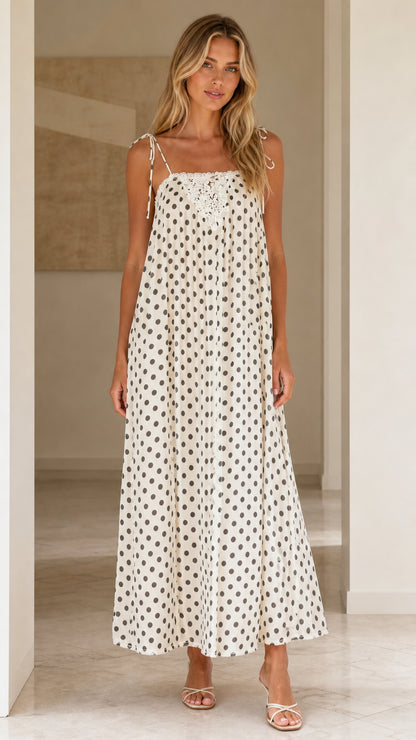 Front view of woman wearing white polka dot maxi dress with tie straps