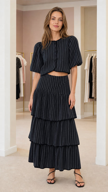 Front view of model wearing black pinstripe crop top and tiered maxi skirt set