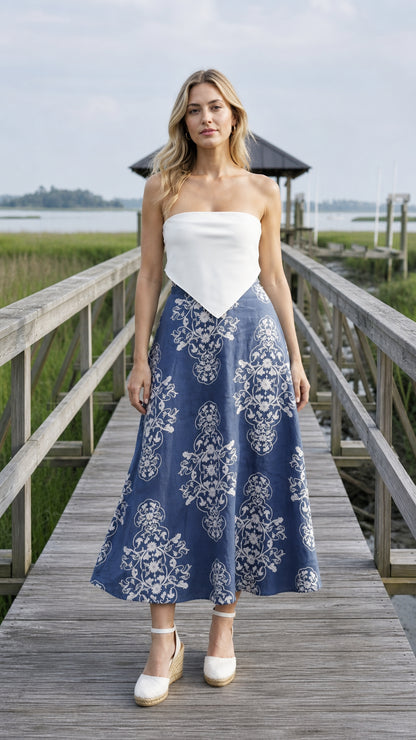 Front view of blue floral midi skirt paired with white top on wooden dock