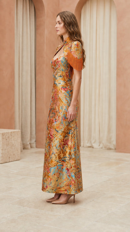 Side profile of model in gold brocade dress with fringe shoulder details