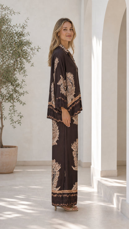 Side profile of model in brown paisley button-down and wide leg pants