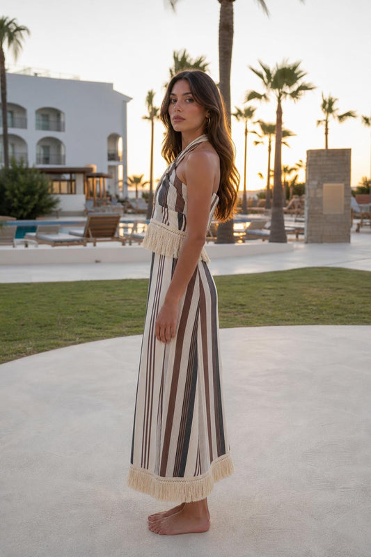 Side profile of model wearing beige stripe halter fringe maxi dress