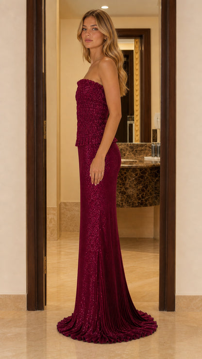 Side view of a burgundy strapless floor-length maxi dress with a softly flared train