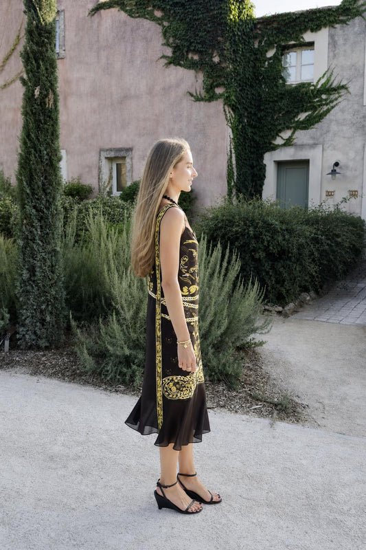 Model wearing black vintage gold print midi dress side view