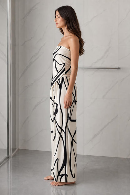 Side profile view of woman wearing beige and black abstract print strapless jumpsuit