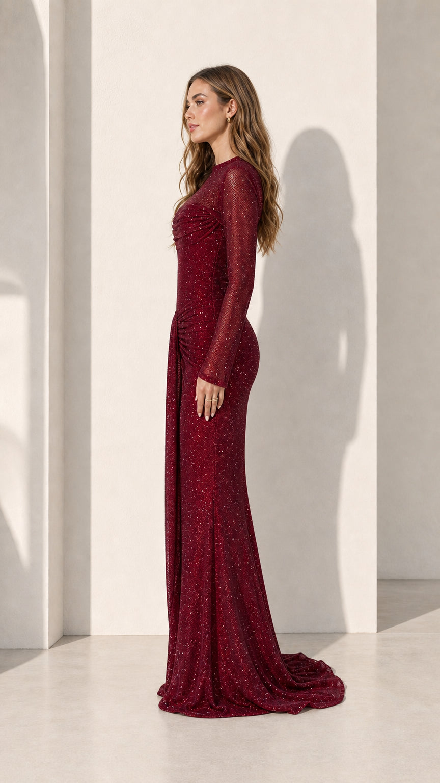Model wearing burgundy long sleeve glitter evening gown, side view