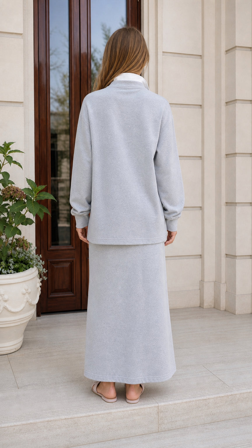 Back view of woman in light grey polo sweatshirt and skirt