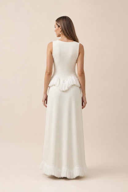 Back view of white fringed peplum maxi dress against neutral studio backdrop