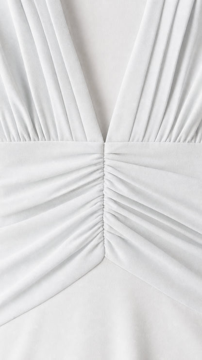 Close-up detail of pleated V-neck and ruched waist on white dress