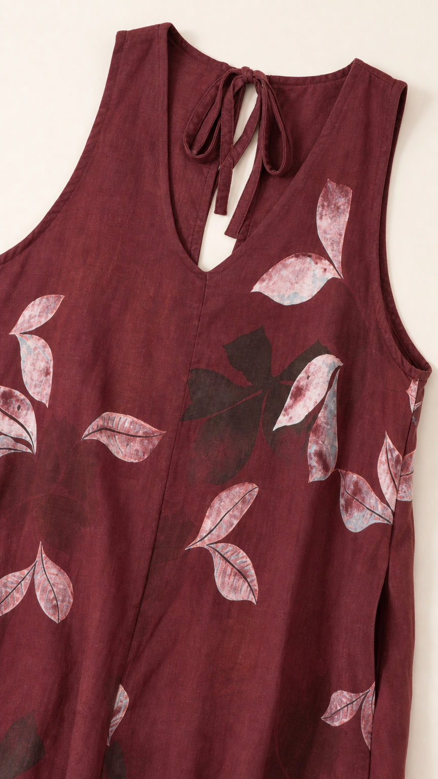 Close-up of V-neck and leaf pattern on burgundy jumpsuit