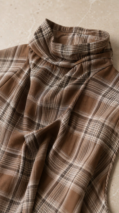 Close-up detail of brown plaid fabric and high neckline