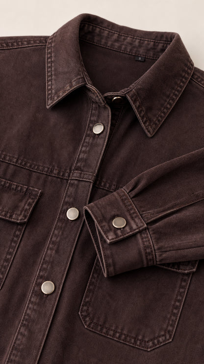Close-up detail of collar, snap buttons, and chest pocket on brown denim dress
