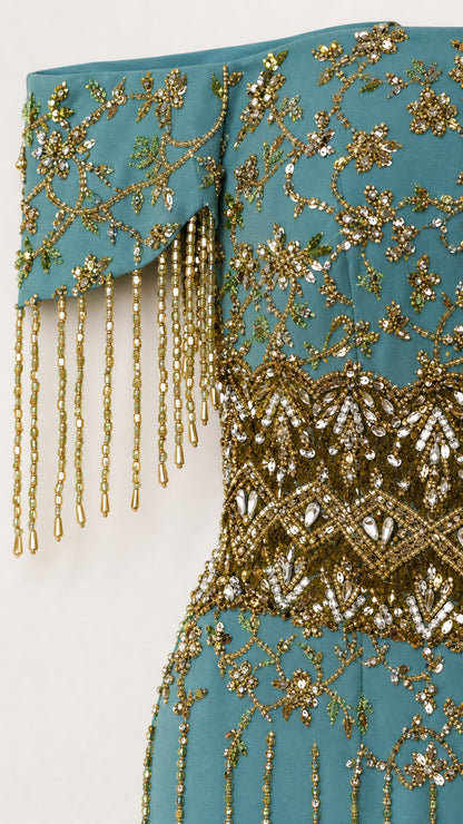 Close-up detail of gold beadwork and fringe on teal dress sleeve