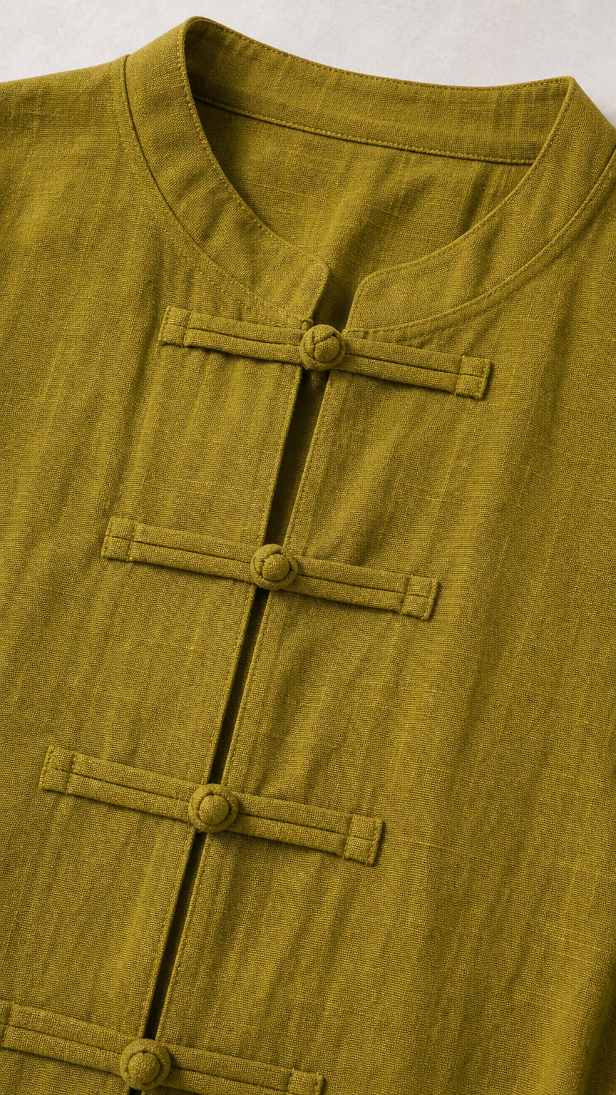 Close-up detail of mandarin collar and knot closures on olive green top