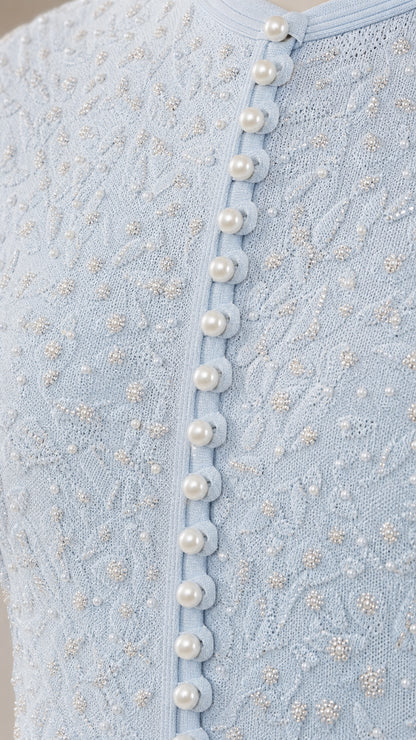 Close-up of textured knit fabric and pearl buttons on light blue dress