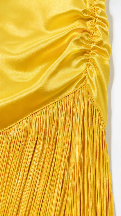 Close-up detail of smooth satin fabric, ruching, and fringe hem