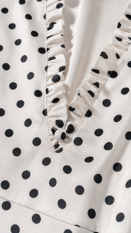Close-up detail of ruffled V-neckline on polka dot dress