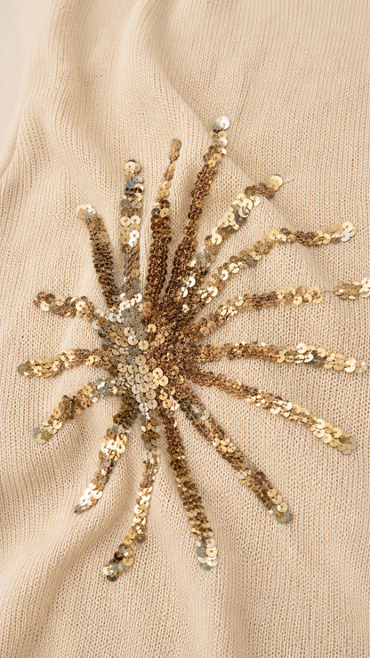 Close-up detail of gold sequin sunburst embroidery on fabric