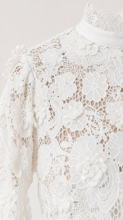 Close-up detail of white floral lace texture and high neckline