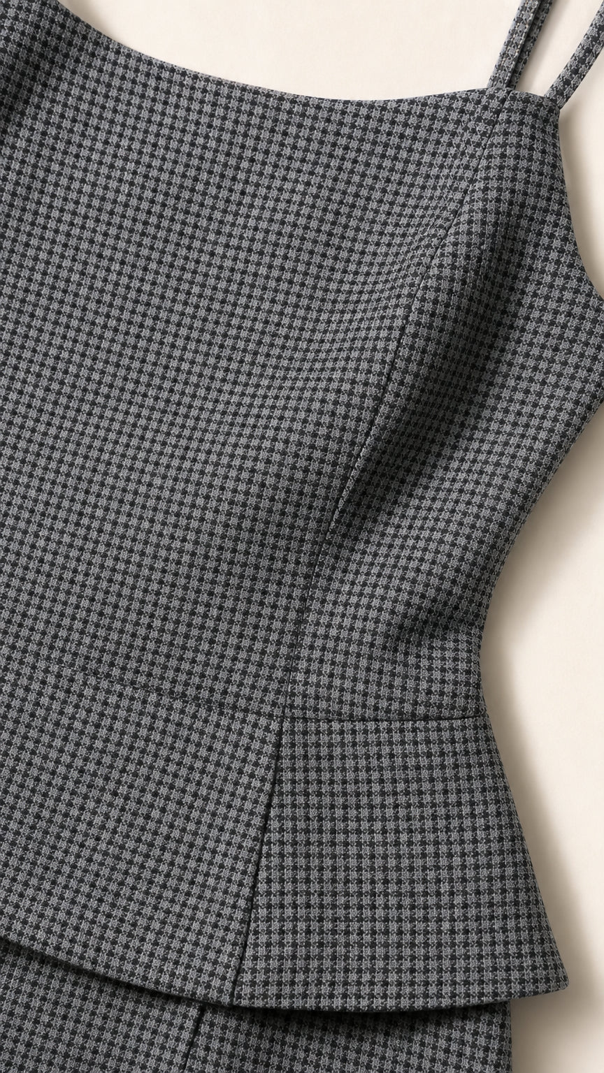 Close-up detail of textured grey houndstooth fabric and peplum hem