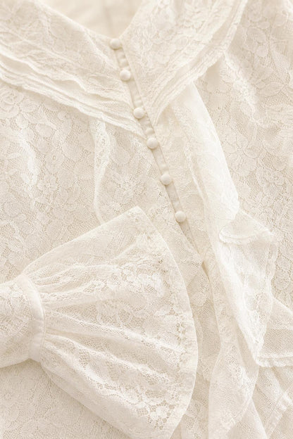Close-up detail of lace texture, buttons, and ruffle trim on white dress