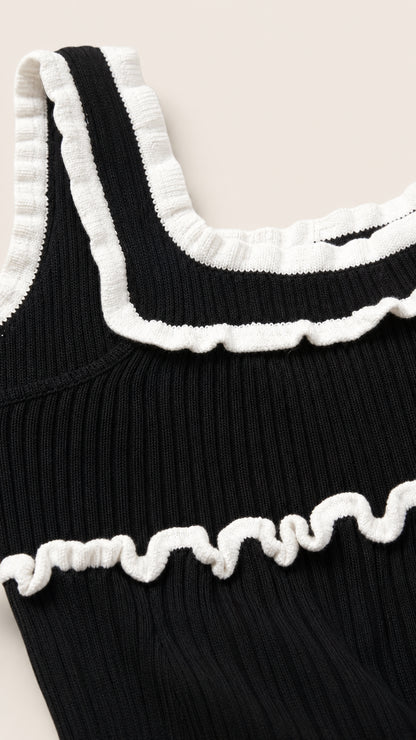 Close-up detail of white lettuce ruffles on black knit top