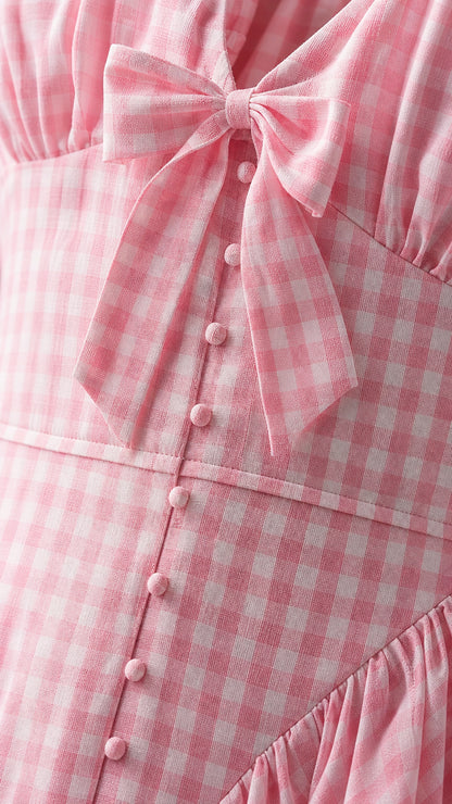 Close up of pink gingham dress bodice with bow and buttons