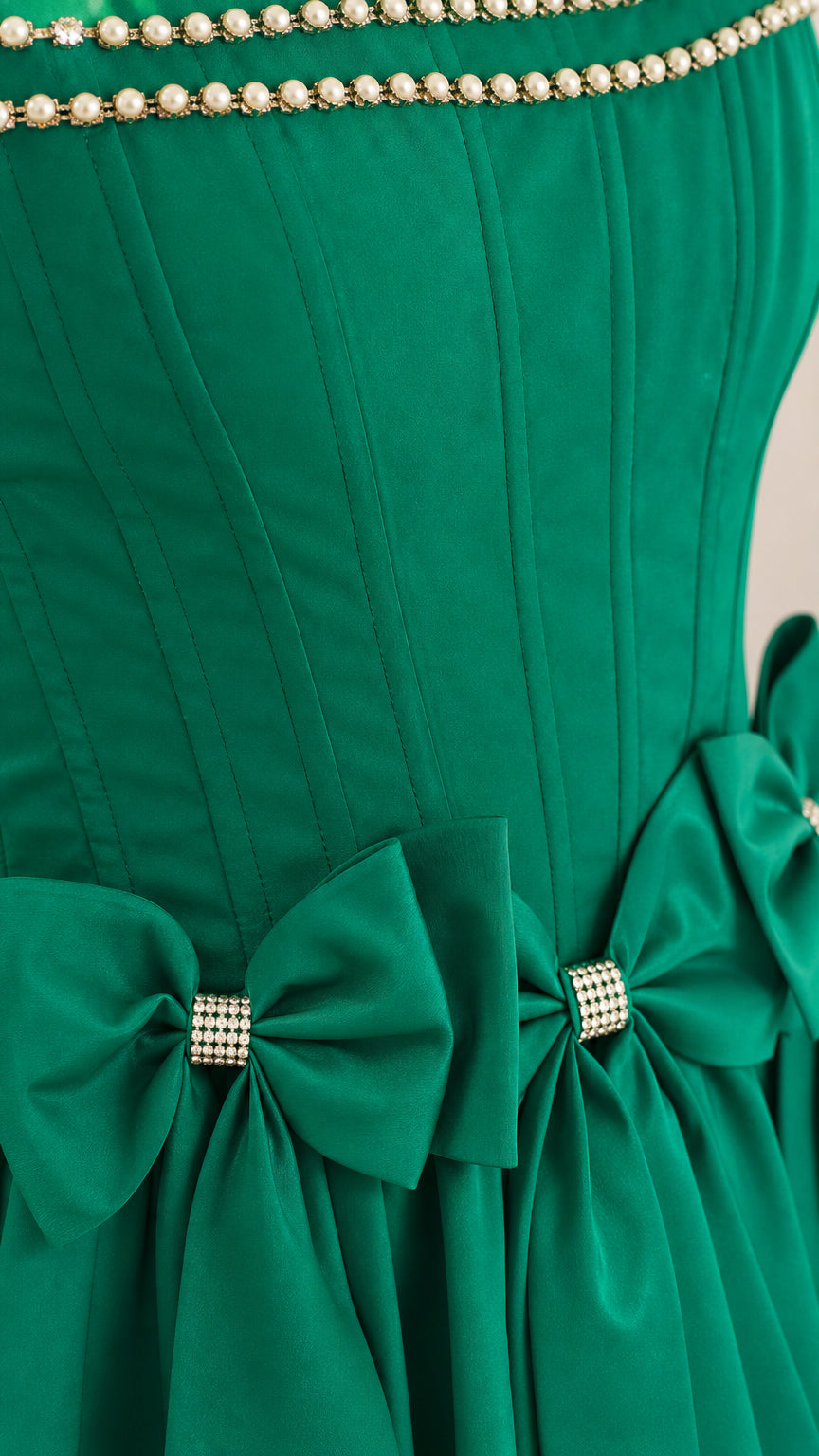 Close-up of pearl trim and rhinestone bows on green dress