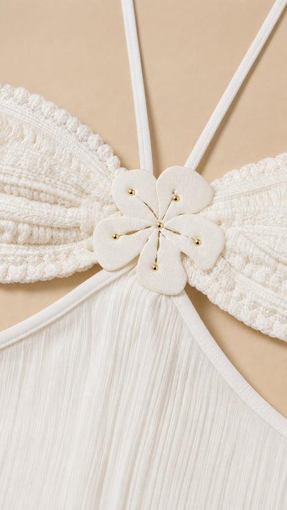 Close-up detail of white bodice with floral appliqué and halter straps