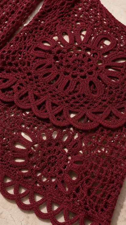 Closeup detail of burgundy open-knit crochet fabric and scalloped hem