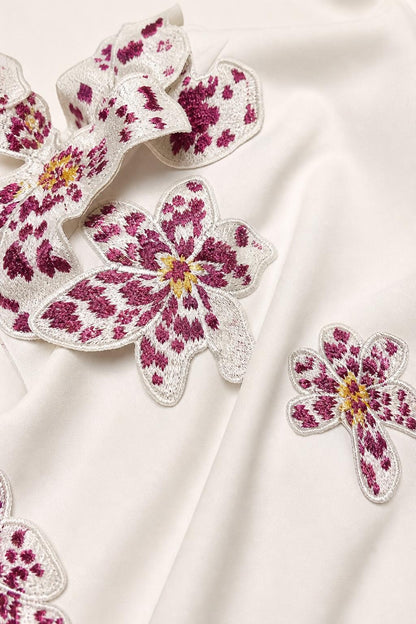Close-up of 3D embroidered floral appliques on smooth white fabric