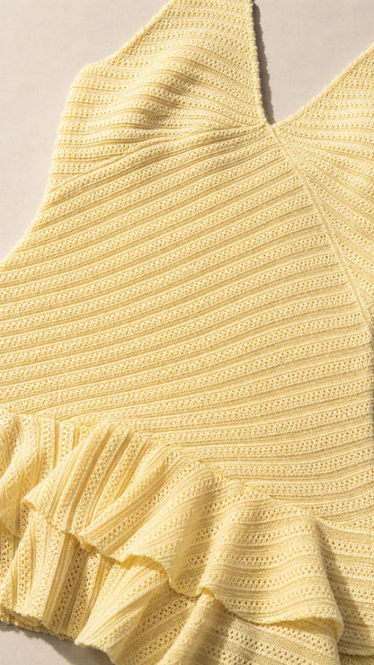 Close-up detail of yellow knit texture and ruffle hem
