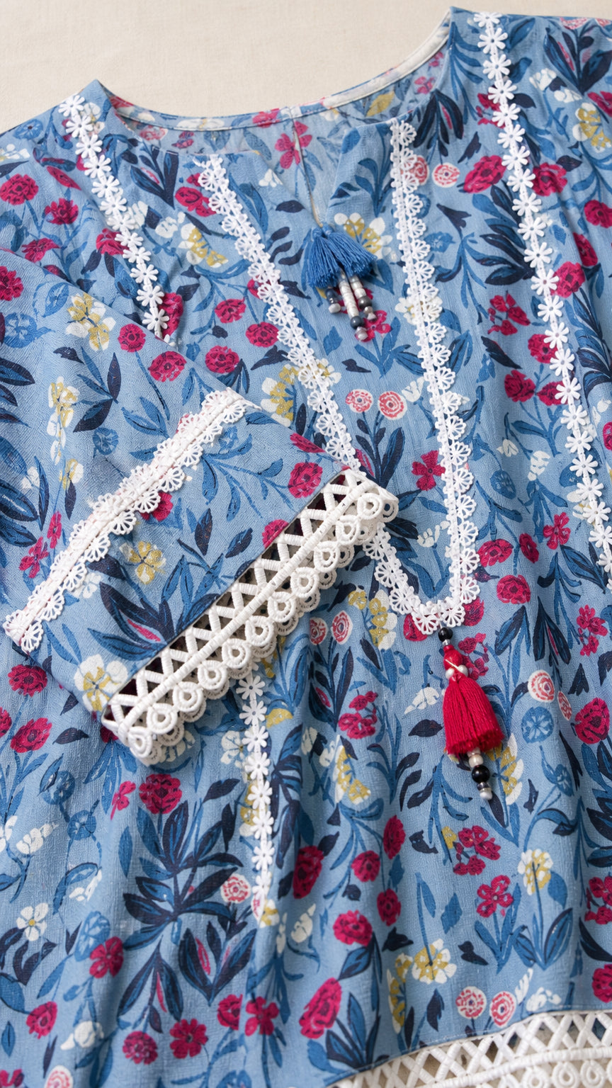 Close-up detail of blue floral tunic neckline with lace trim and tassels