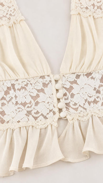 Close-up of lace trim and button details on cream crop top