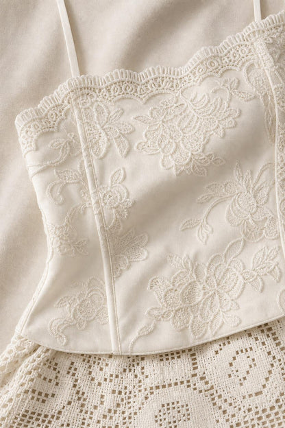 Close-up detail of white embroidered corset top and patterned lace fabric