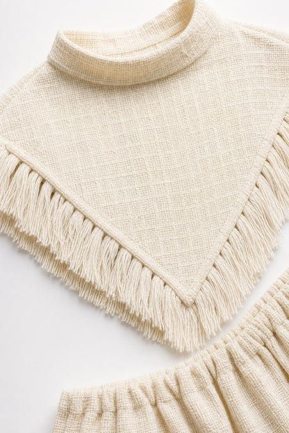Close-up detail of mock neck and fringe hem