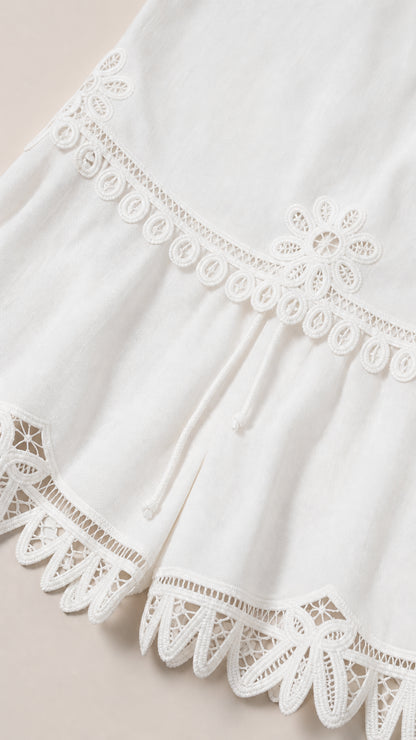 Close-up detail of embroidery and lace hem on white shorts