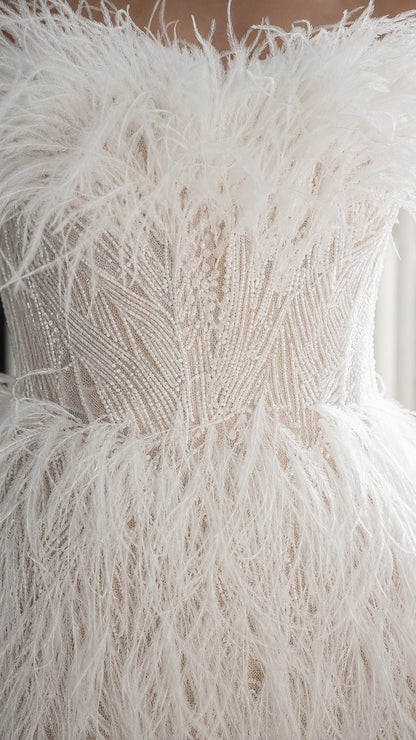 Close up of intricate beadwork and feather texture on white dress