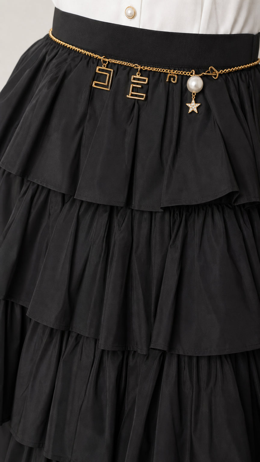 Close-up detail of the black tiered ruffles and chain belt accessory