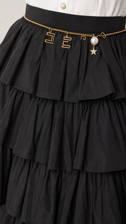 Close-up detail of the black tiered ruffles and chain belt accessory