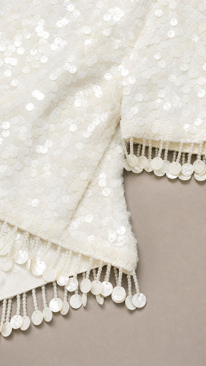 Close-up of white sequin fabric and fringe trim