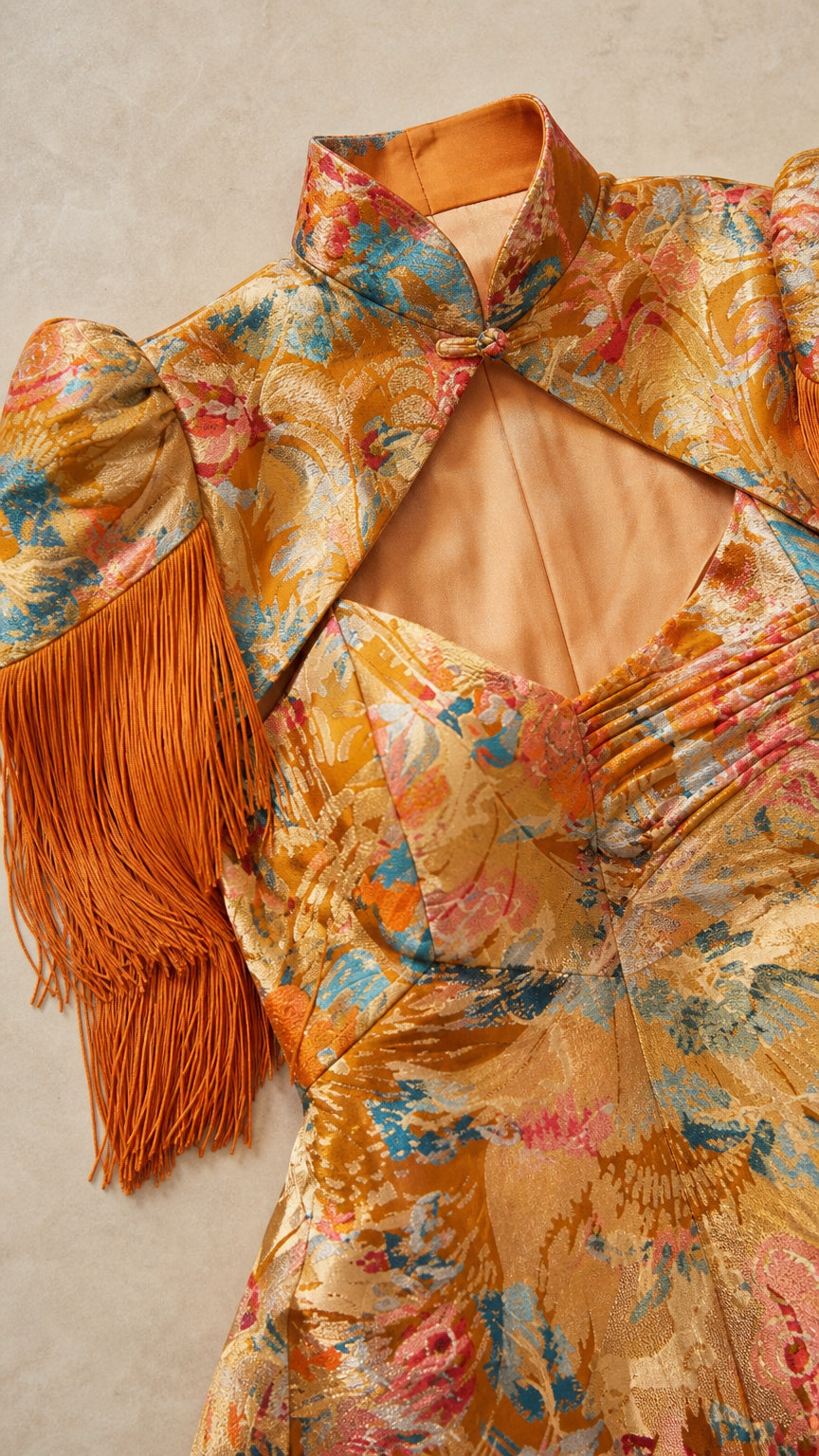 Close-up of gold brocade fabric, mandarin collar, and cutout keyhole bodice