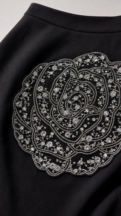 Close-up of intricate rhinestone and bead rose applique on black skirt