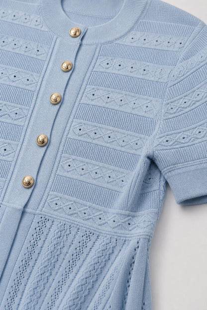 Close-up detail of buttons and knit pattern on light blue dress