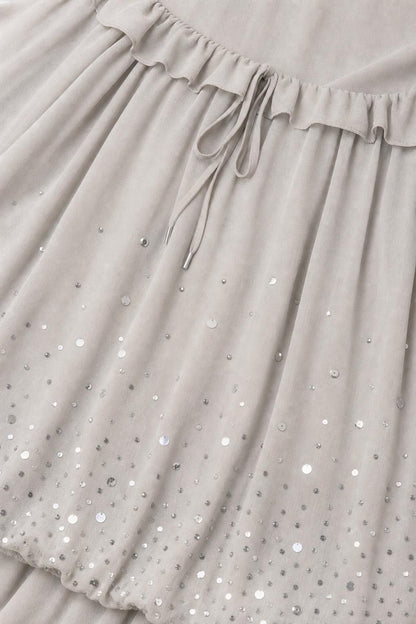 Close-up detail of sequin embellishments and drawstring waist on grey chiffon dress