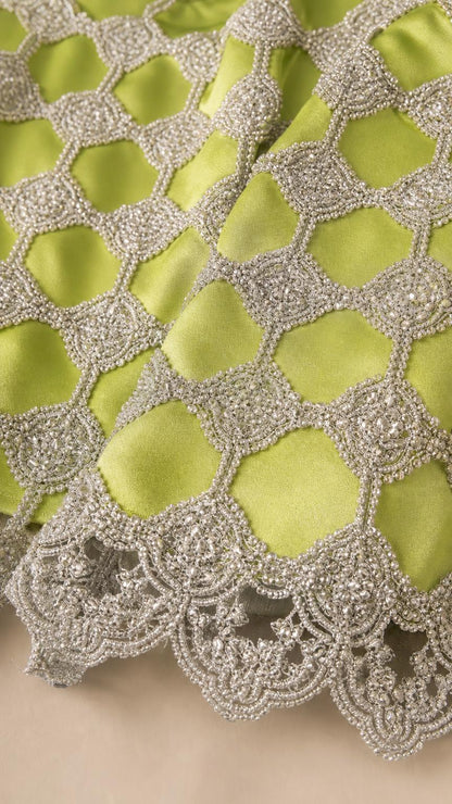 Close-up detail of metallic lattice beadwork and scalloped hem