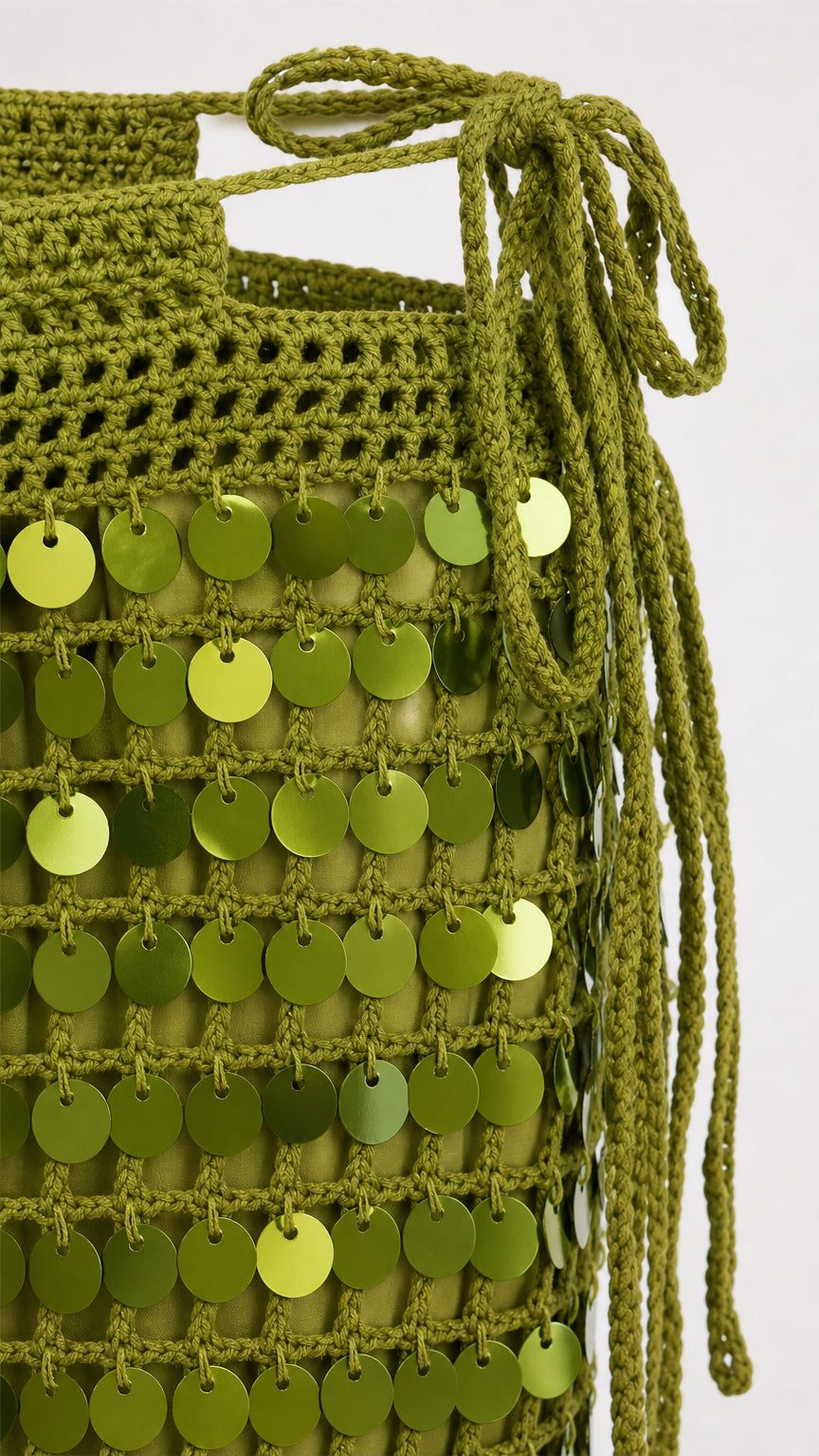 Close-up detail of olive crochet texture and shiny circular sequins