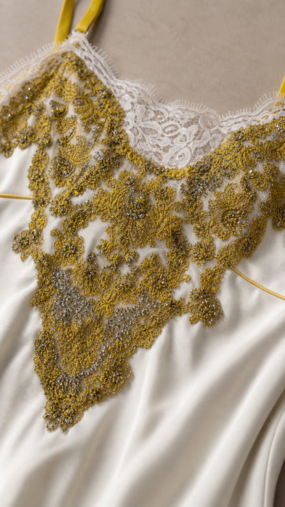 Close-up detail of white lace and gold bead embroidery on dress bodice