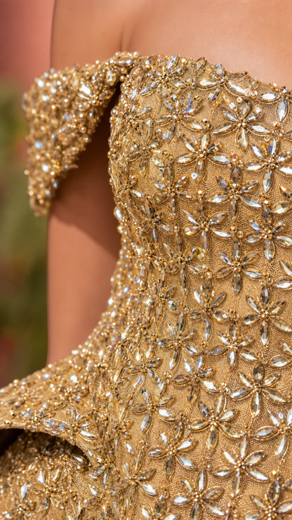 Close-up detail shot of intricate crystal beadwork and peplum construction on gold gown